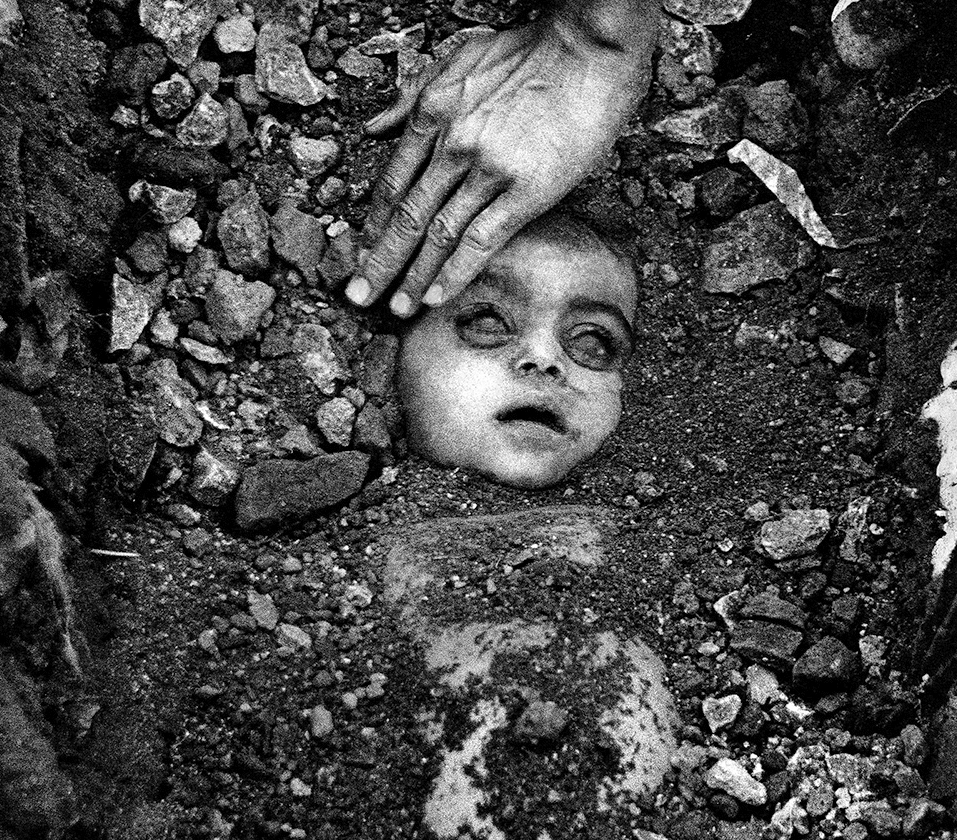 1984 में गैस त्रासदी में मरे बच्चे को दफनाते हुए ली गई फोटो।