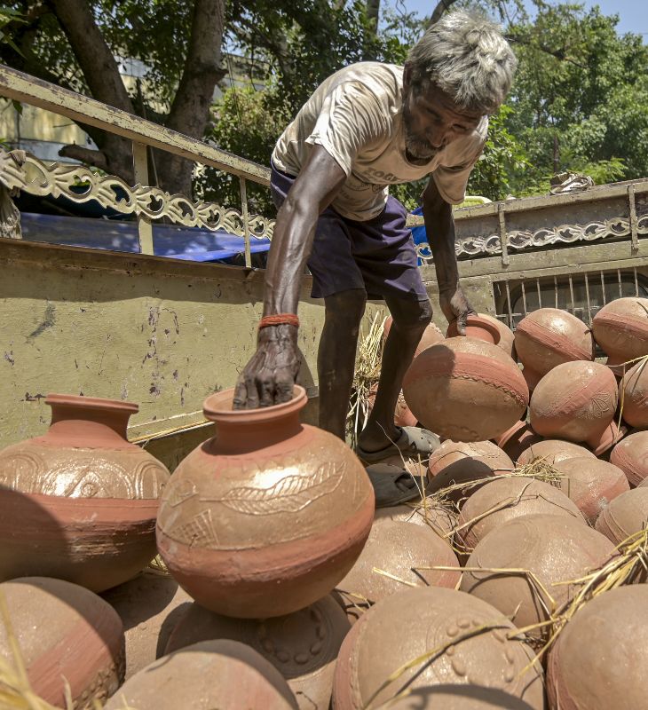 प्रयागराज में एक मजदूर तेज धूप के बीच गाड़ी से मिट्टी के घड़े उतारता नजर आया।
