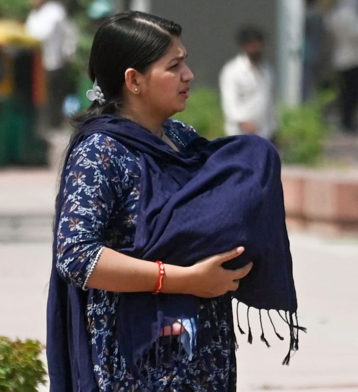 दिल्ली में एक मां अपने बच्चे को तेज धूप से बचाने के लिए ढकती दिखी।