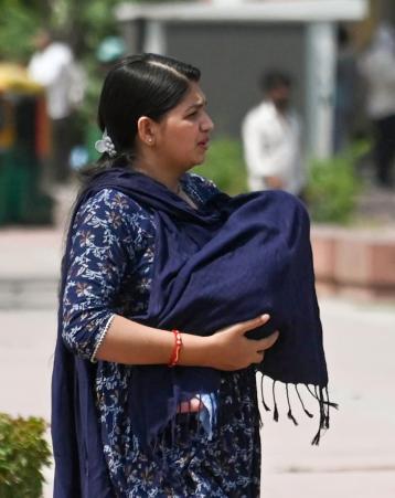 दिल्ली में चिलचिलाती धूप से अपने बच्चे को बचाती मां।