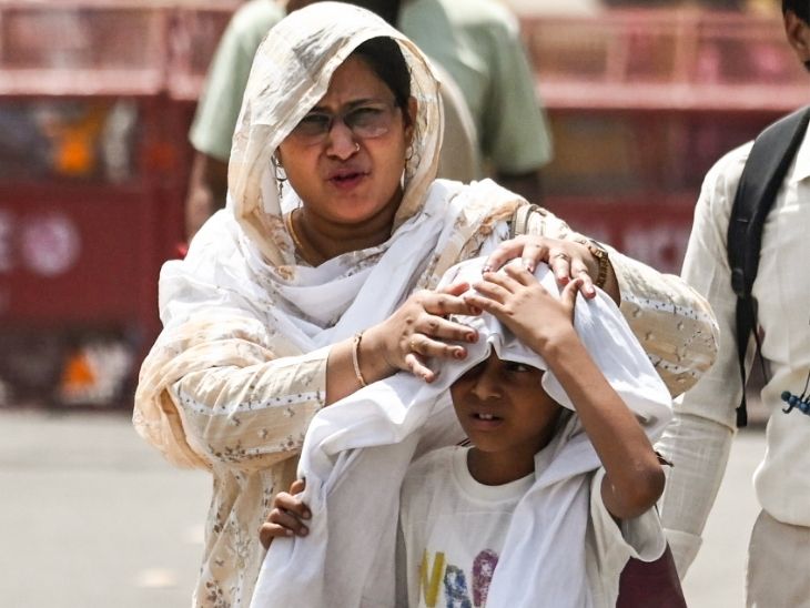 दिल्ली में लाल किले के पास अपने बच्चे को गमछे से ढंकती एक मां।