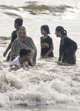 मुंबई के वर्सोवा बीच पर गर्मी के बीच समुद्र किनारे मस्ती करते लोग।