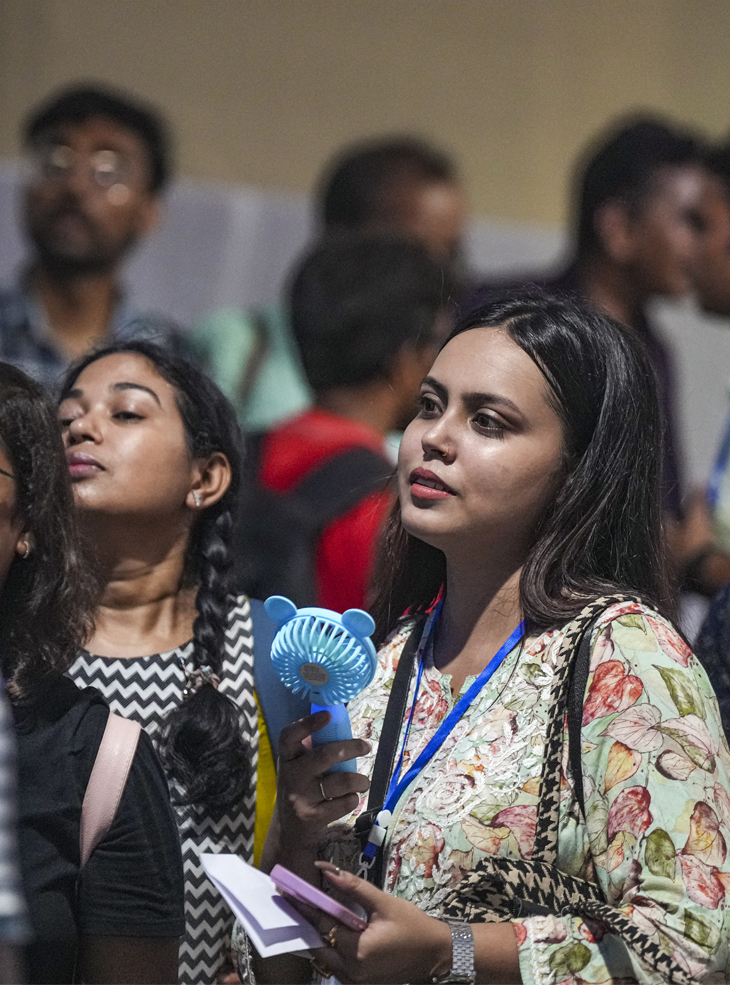 कोलकाता में ईवीएम डिस्ट्रिब्यूशन सेंटर में मतदान कर्मी गर्मी से बचने के लिए फैन का इस्तेमाल करती हुई।