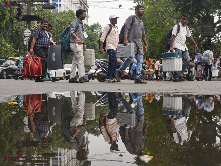 मतदान कर्मी ईवीएम मशीन लेकर अपने-अपने बूथ की ओर जाते हुए।