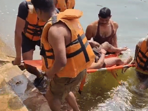 नहर में डूबे पिता यमन गंजीर के शव को बरामद करने के बाद ले जाते गोताखाेर