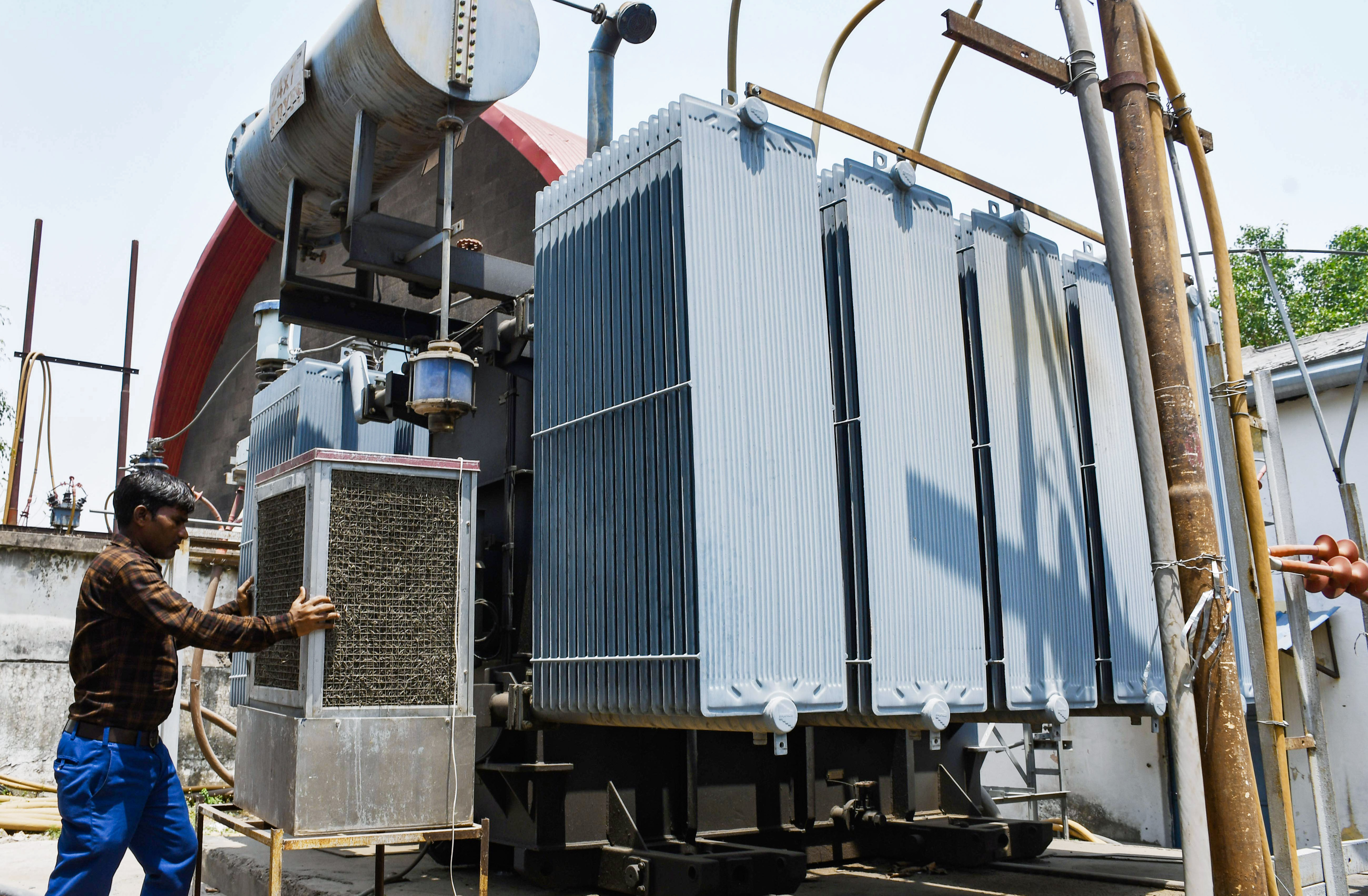 प्रयागराज में दिन के समय ट्रांसफॉर्मर को आग लगने से बचाने के लिए कूलर लगा रहा है।