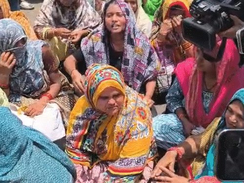 महिलाएं सड़क पर बैठकर विरोध कर रही हैं।