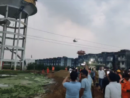 पानी की टंकी पर फंसे बच्चों को बचाने के लिए एयरफोर्स ने हेलिकॉप्टर भेजा। उसे देखने के लिए लोगों की भीड़ जमा हो गई।