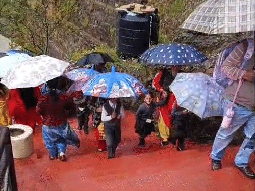 शिमला में बारिश के बीच घरों को लौटते हुए बच्चे।