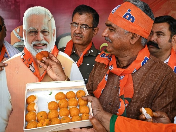 3 राज्यों के चुनाव में जीत के बाद दिल्ली में भाजपा कार्यकर्ता पीएम मोदी की फोटो को मिठाई को खिलाते हुए।