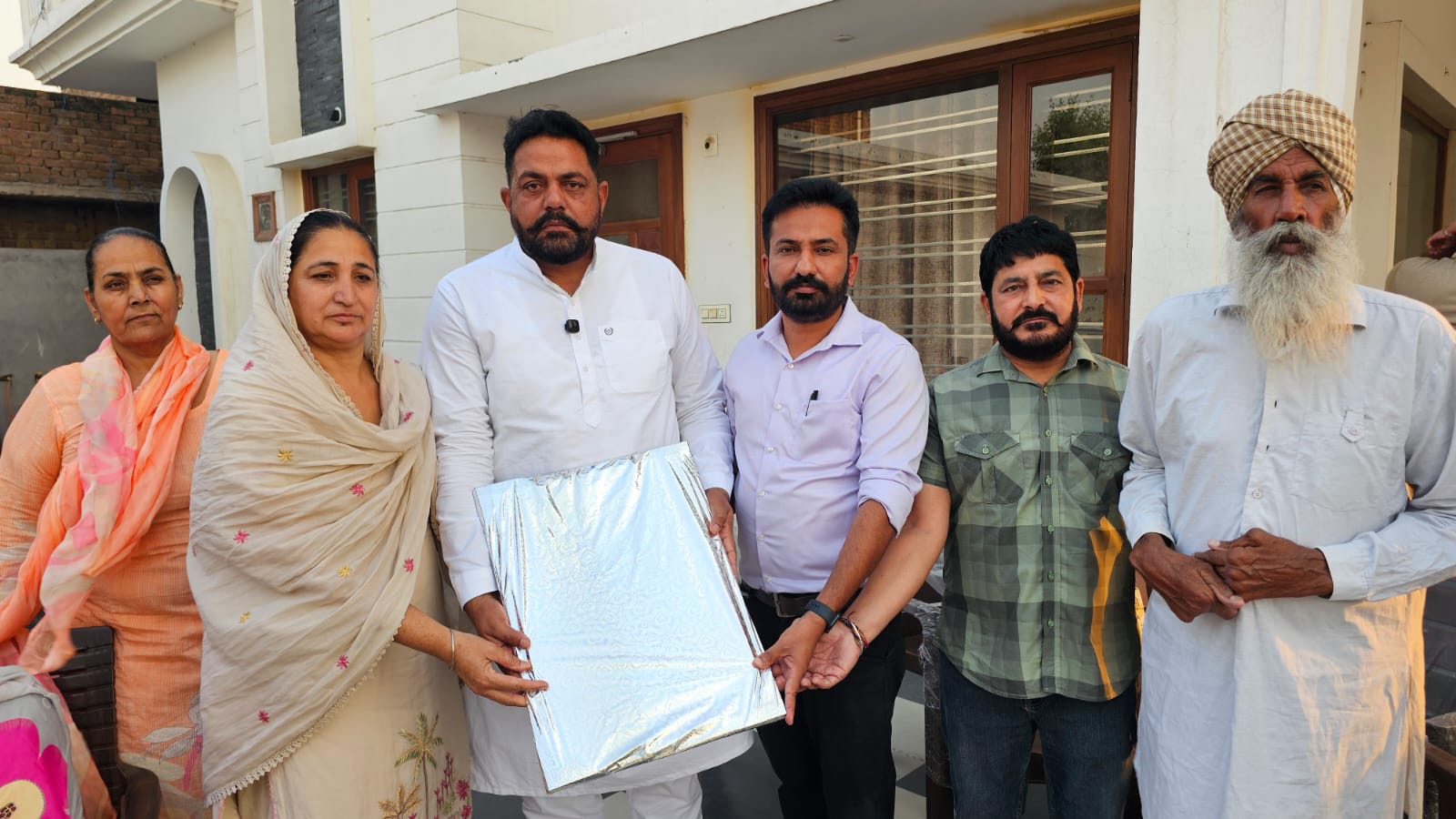परिवार को गिफ्ट देते हुए लोग।
