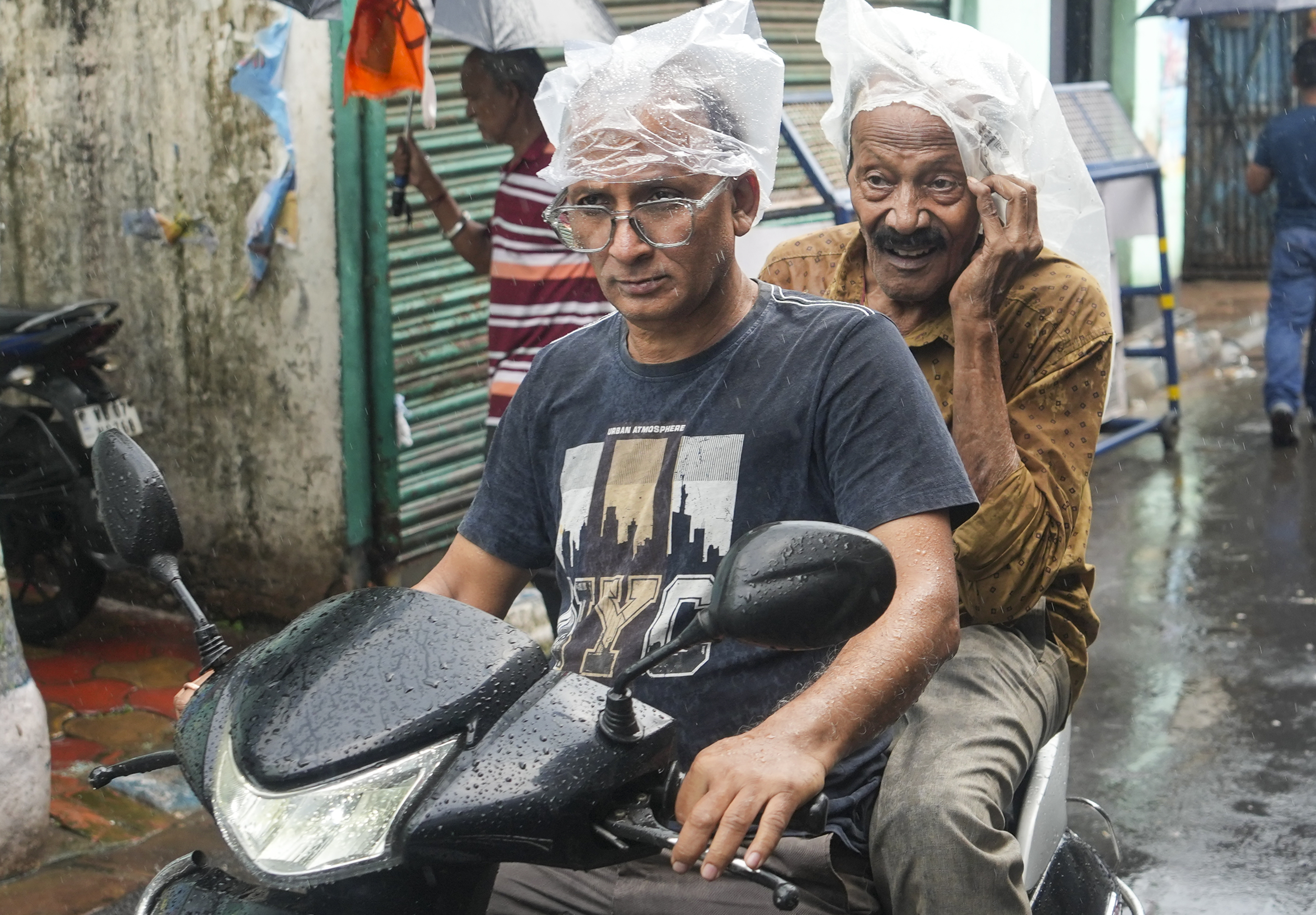 कोलकाता में बारिश के बीच आवाजाही करते यात्री। यहां आज बारिश का ऑरेंज अलर्ट है।