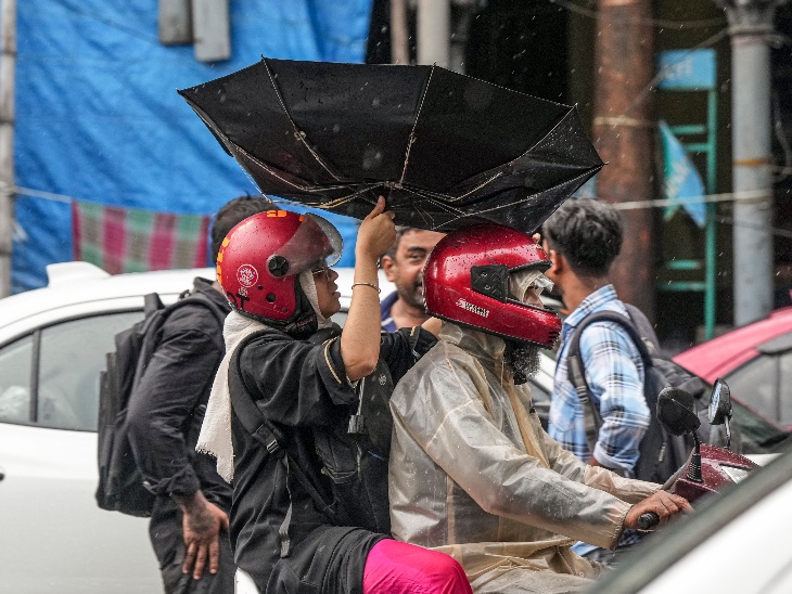 कोलकाता में बारिश के दौरान तेज हवाएं भी चलीं। इसके कारण यात्री का छाता हवा में पलट गया।
