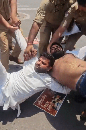 सपा के कार्यकर्ता पुलिस के हिरासत में लेने के दौरान सड़क पर लेट गए। उन्हें पुलिस ने जबरदस्ती उठा लिया।
