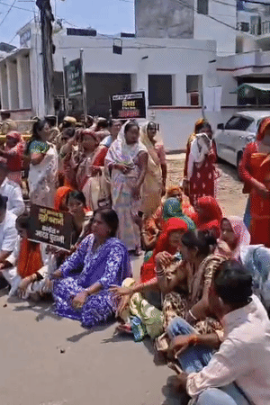महिलाएं धूप में बैठकर सपा सांसद के खिलाफ नारेबाजी कर रही हैं।