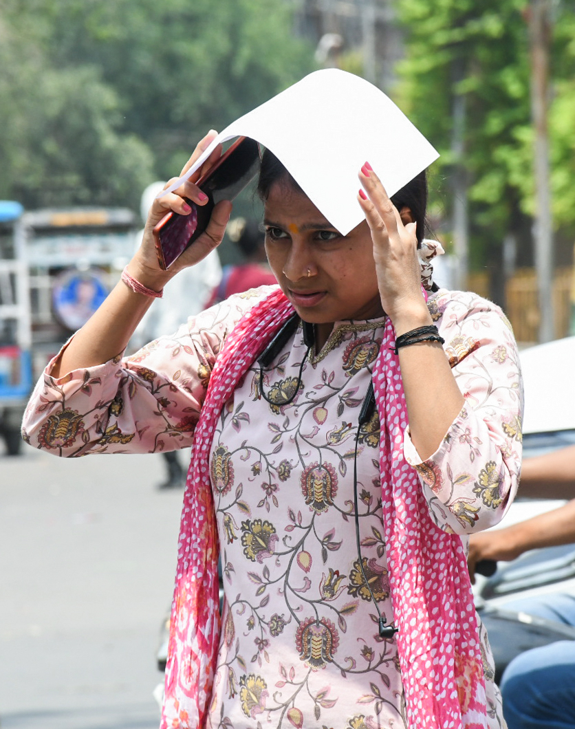 यूपी के कानपुर में तेज धूप में पेपर से खुद को ढंकती महिला।