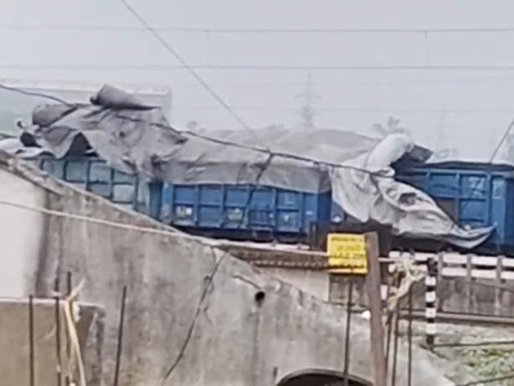 तेज हवाओं से तिरपाल उड़ कर बिजली की तारों में फंस गया