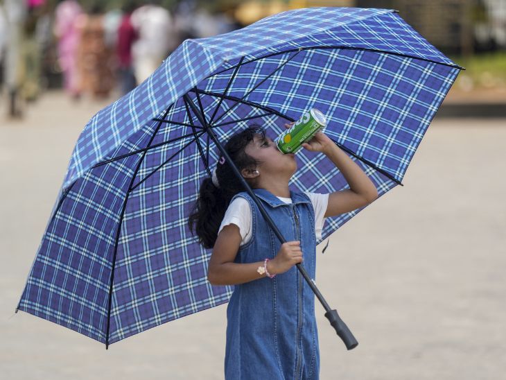 मुंबई में छाता लिए एक बच्ची गर्मी में कोल्ड ड्रिंक पीती दिखाई दी।