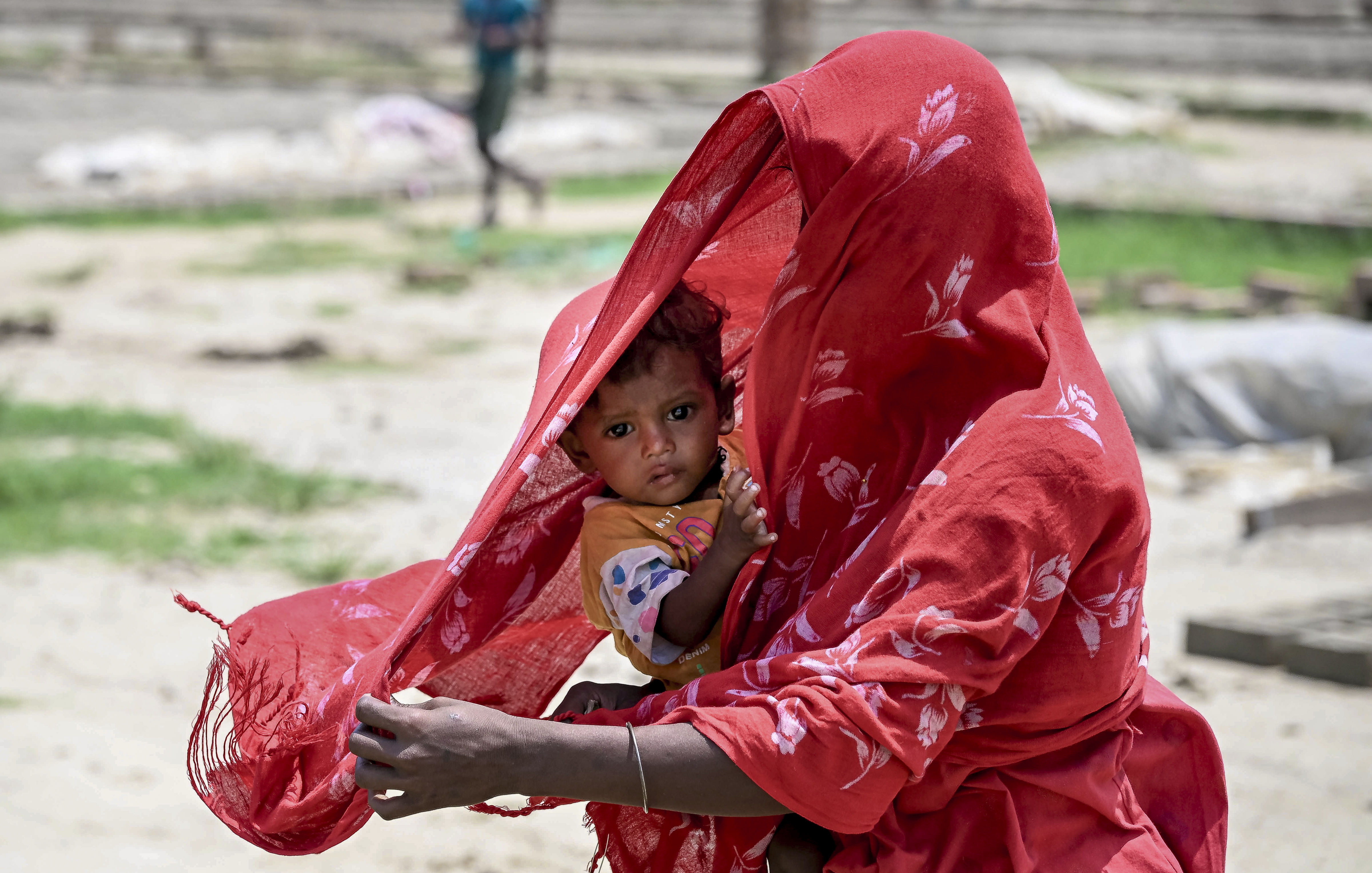 पश्चिम बंगाल के नादिया में अधिकतम तापमान 38°C के करीब रहा। धूप से बचाने के लिए बच्चे को कपड़े से ढंककर ले जाती महिला।