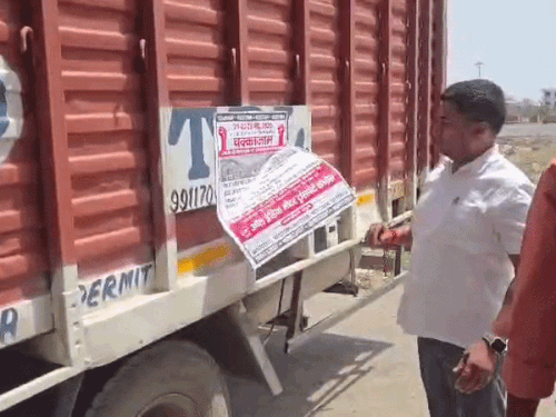 गुरुग्राम में ट्रकों की हड़ताल के दौरान अपने वाहन पर पोस्टर लगाता ट्रांसपोर्टर।