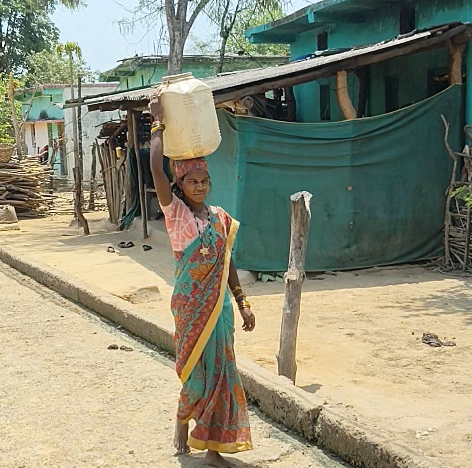भीषण गर्मी में सिर पर प्लास्टिक का डब्बा रखकर पानी लेने जा रही महिला।
