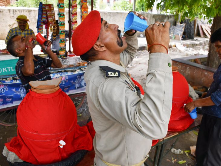 प्रयागराज में रविवार को एक ट्रैफिक पुलिसकर्मी तेज धूप और गर्मी के बीच प्यास बुझाता दिखा।