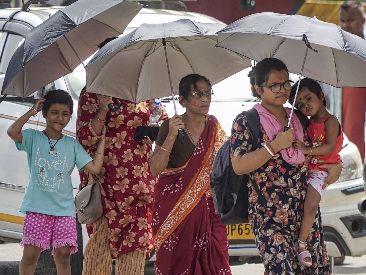 वाराणसी में रविवार को लोग हीटवेव के बीच सड़कों पर छाता लेकर चलते दिखाई दिए।
