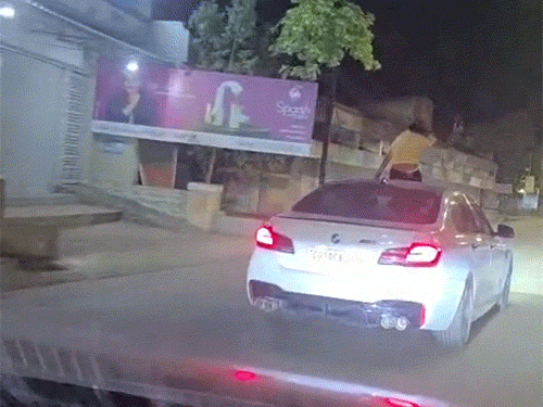 BMW कार की सनरूफ खोलकर डांस करती रही युवती।
