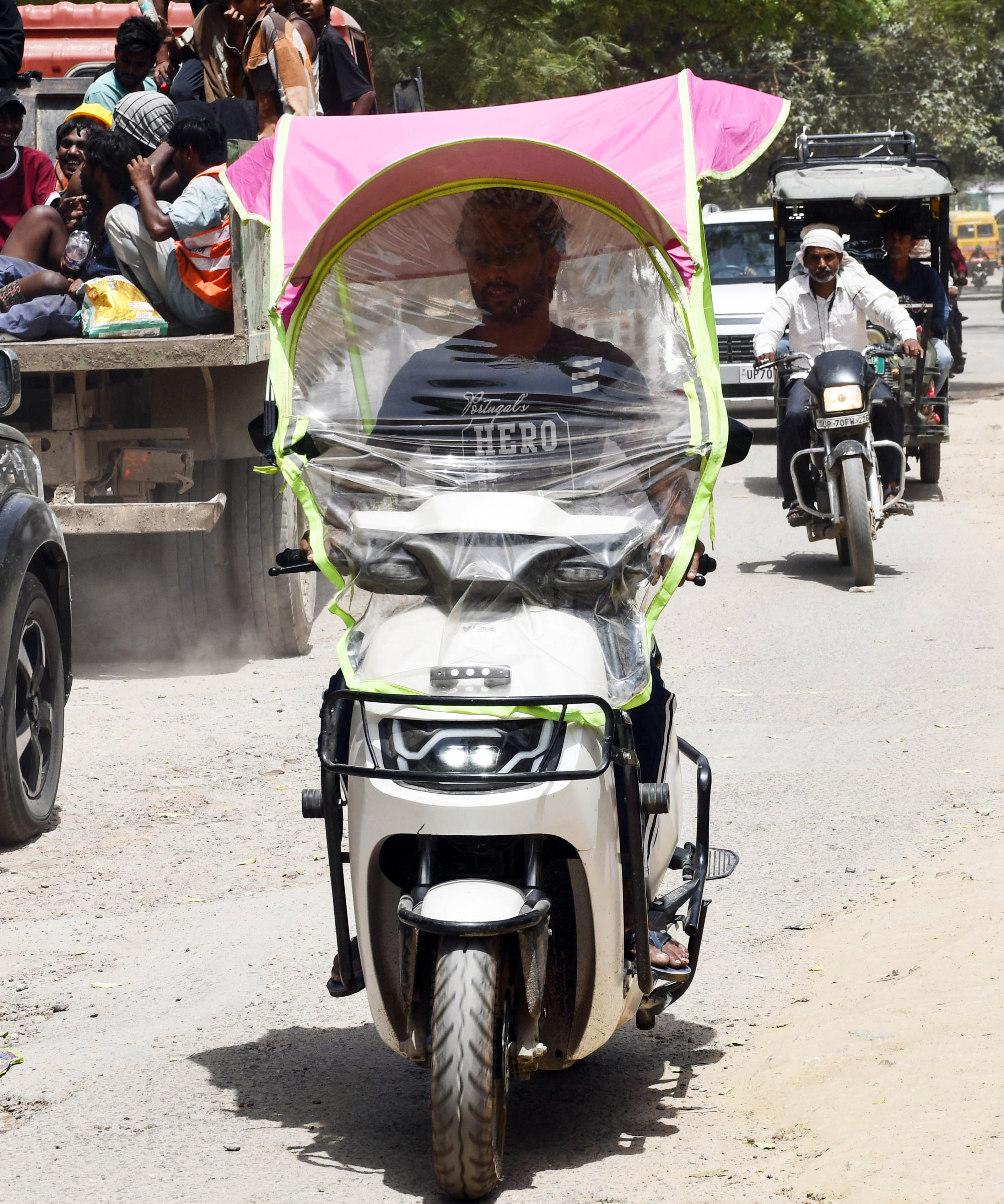 उत्तर प्रदेश के प्रयागराज में एक शख्स तेज धूप से बचने के लिए स्कूटी पर कवर लगाकर निकला।