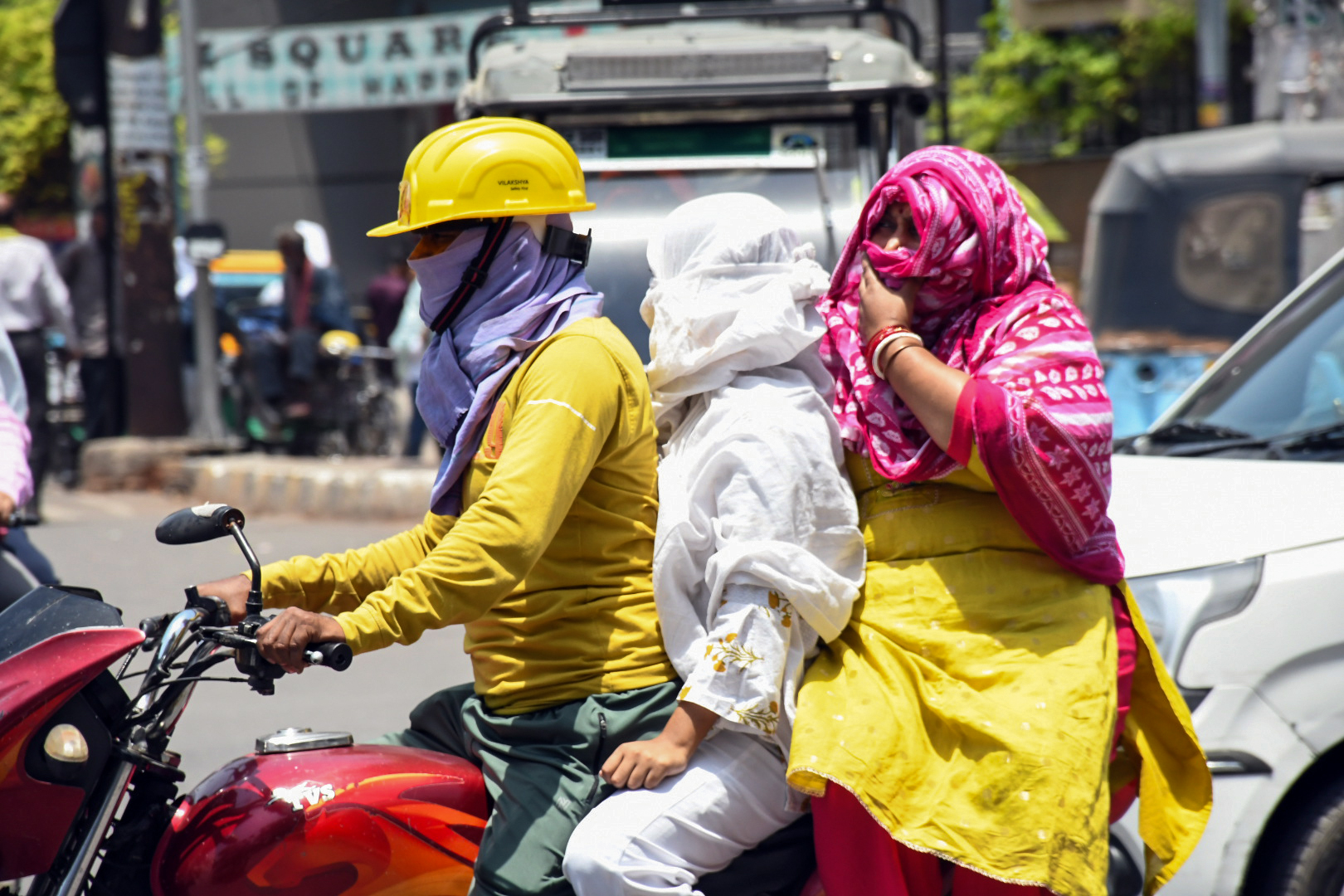 उत्तर प्रदेश के कानपुर में 44°C तापमान के बीच मुंह ढंककर सड़क से गुजरता एक परिवार।