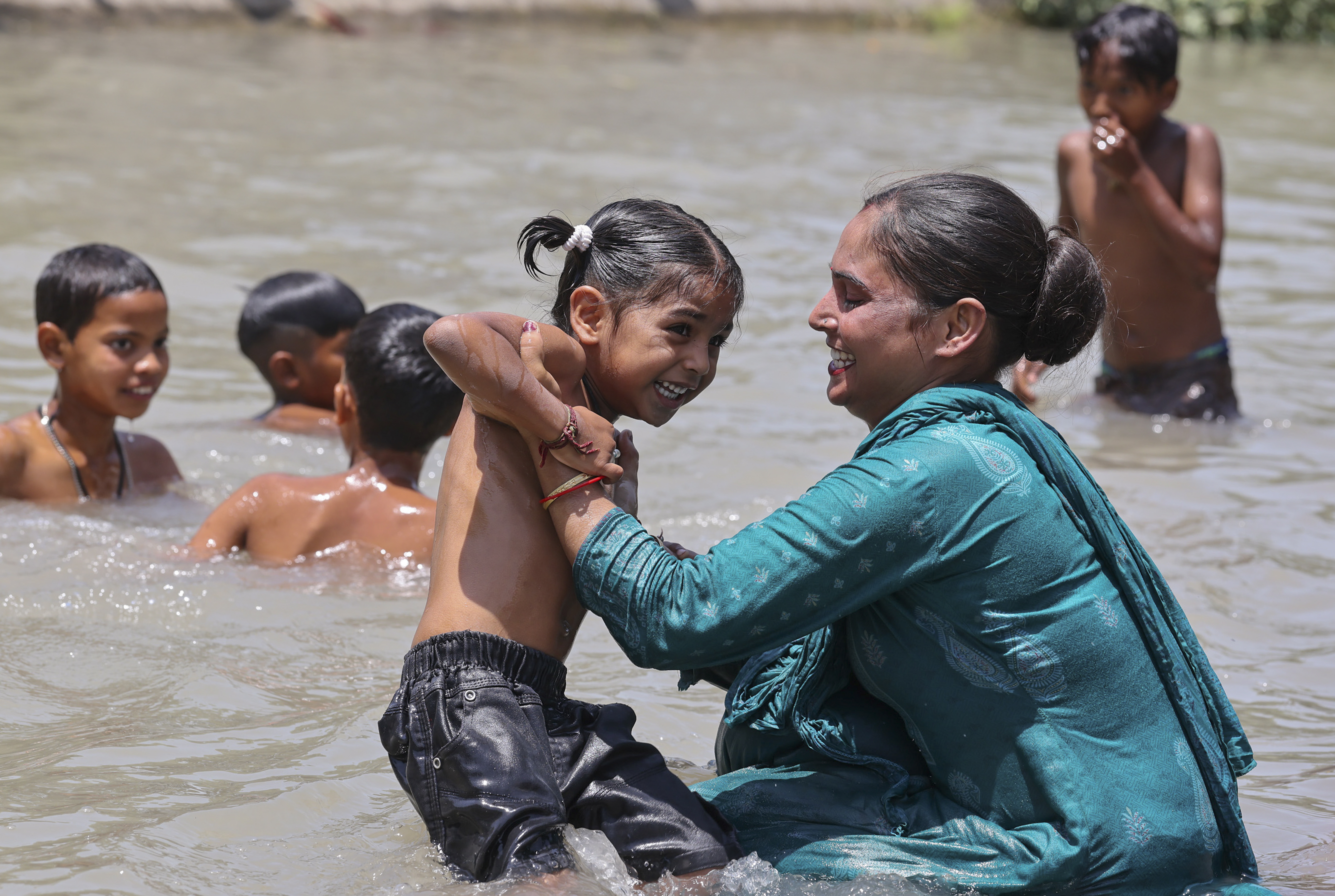 जम्मू में तेज गर्मी का असर जारी है। यहां पर एक इलाके में नहर में नहाते लोग।