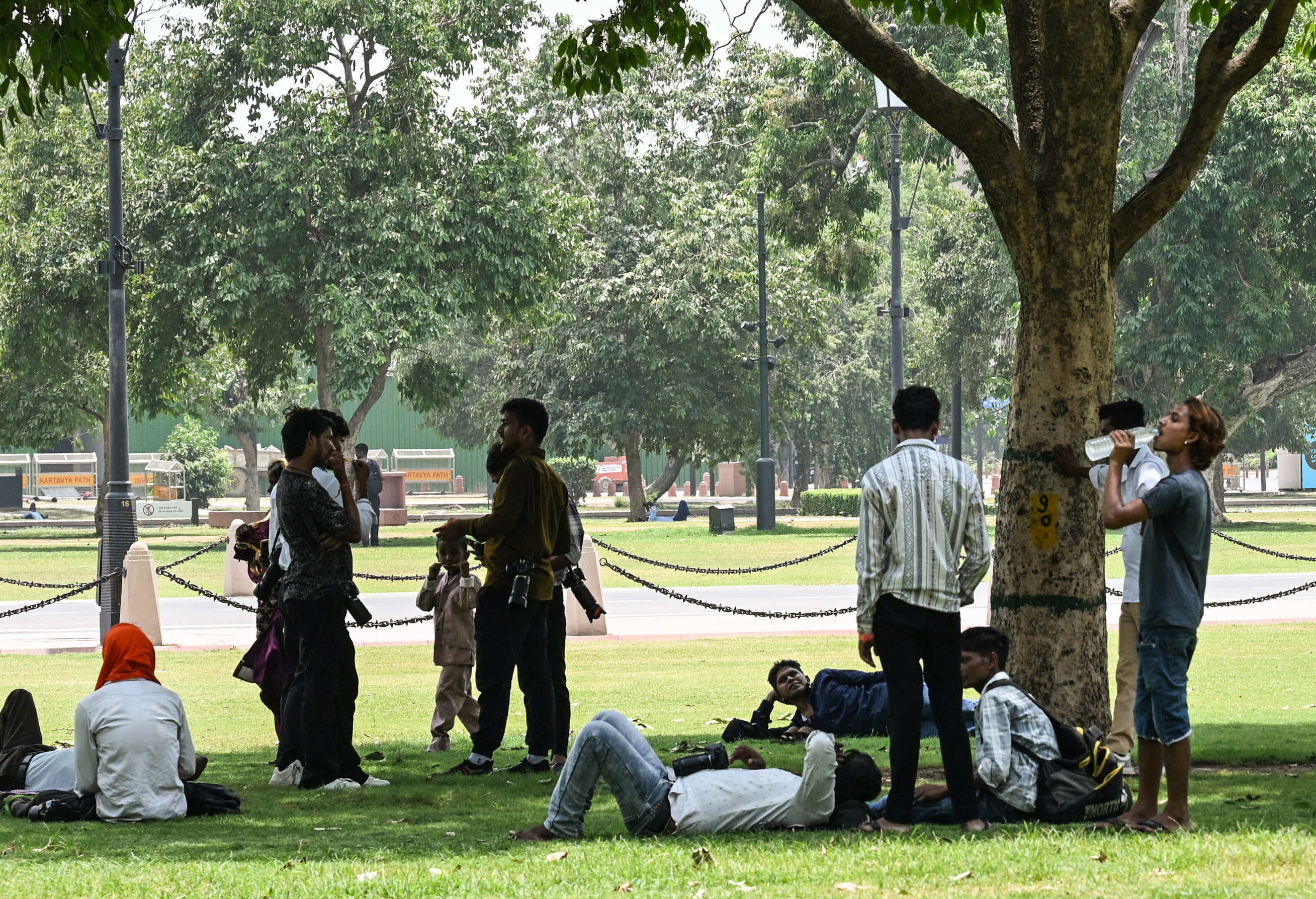दिल्ली के कर्तव्य पथ पर तेज गर्मी से बचने के लिए लोगों ने पेड़ की छांव का सहारा लिया।