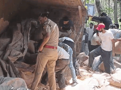 ट्रक से मक्के की बोरियां हटाते हुए पुलिसकर्मी और स्थानीय लोग।