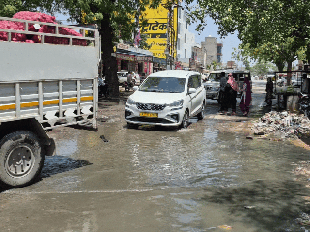 गंदे पानी और टूटी सड़क से निकलती गाड़ियां।