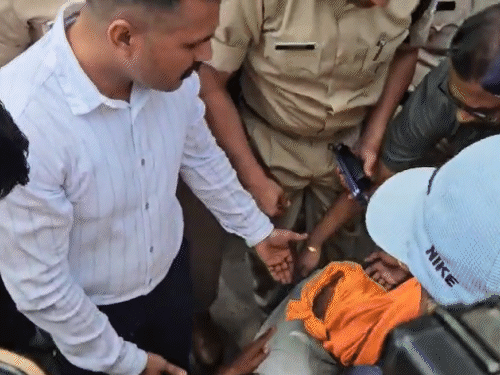 बेहोश होकर गिरे किसान की मदद करते पुलिसकर्मी।