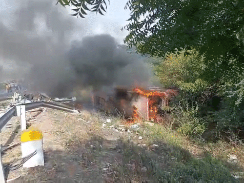 टक्कर के बाद एक बस सड़क किनारे पलट गई और उसमें आग लग गई.