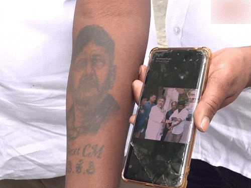 डीके शिवकुमार का एक समर्थक अपने हाथ में उनका टैटू बनवाकर आवास के बाहर पहुंचा।