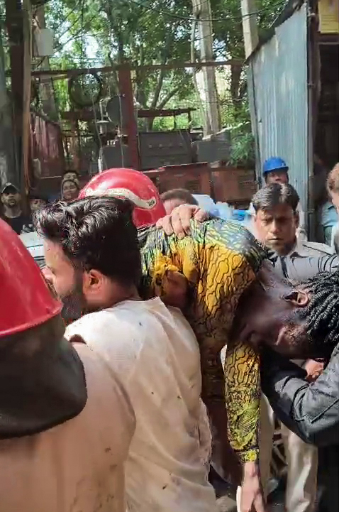 होटल से रेस्क्यू की गई विदेशी महिला को कंधे पर उठाकर ले जाता एक व्यक्ति।