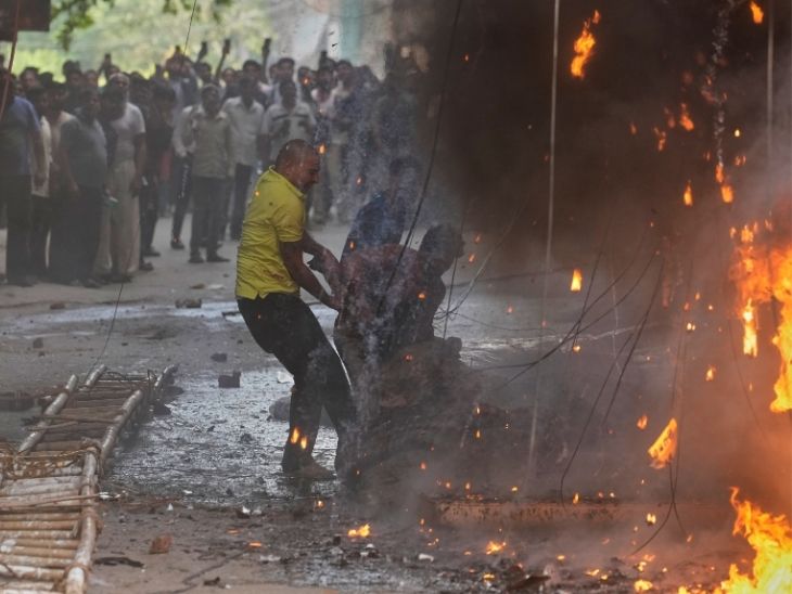 आग के बीच स्थानीय वहां मौजूद लोगों को बचाने की कोशिश कर रहा है।