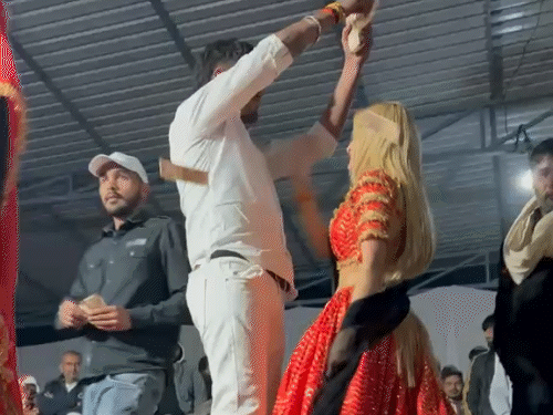 स्टेज शो के दौरान डांसर पर नोट उड़ाता एक युवक।