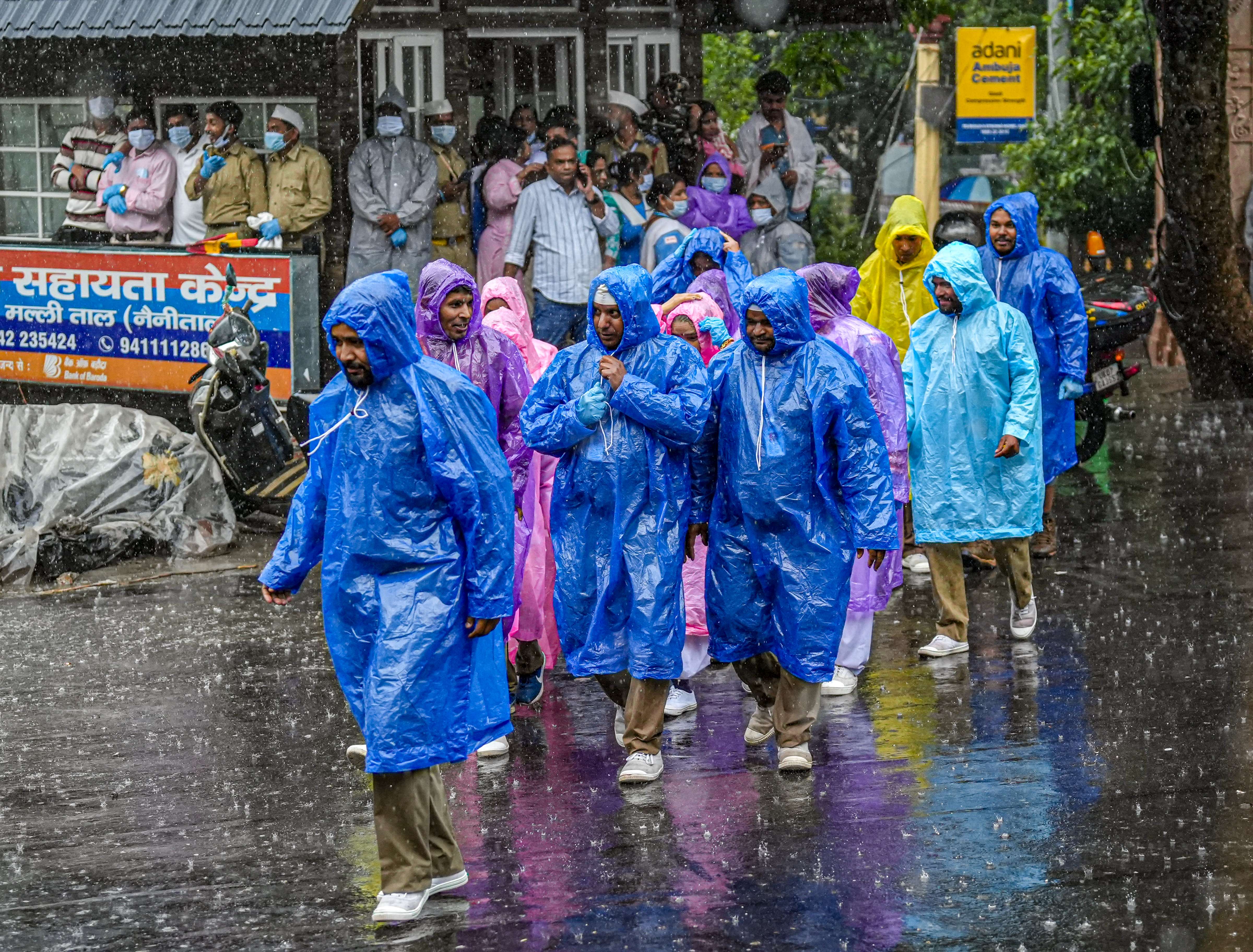 उत्तराखंड के नैनीताल में बारिश के दौरान लोग खुद को ढककर बाहर निकल रहे हैं।