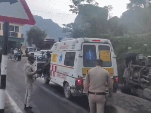 बद्रीनाथ राष्ट्रीय राजमार्ग पर पलटा टेंपो ट्रैवलर और घायलों की मदद करते पुलिसकर्मी।
