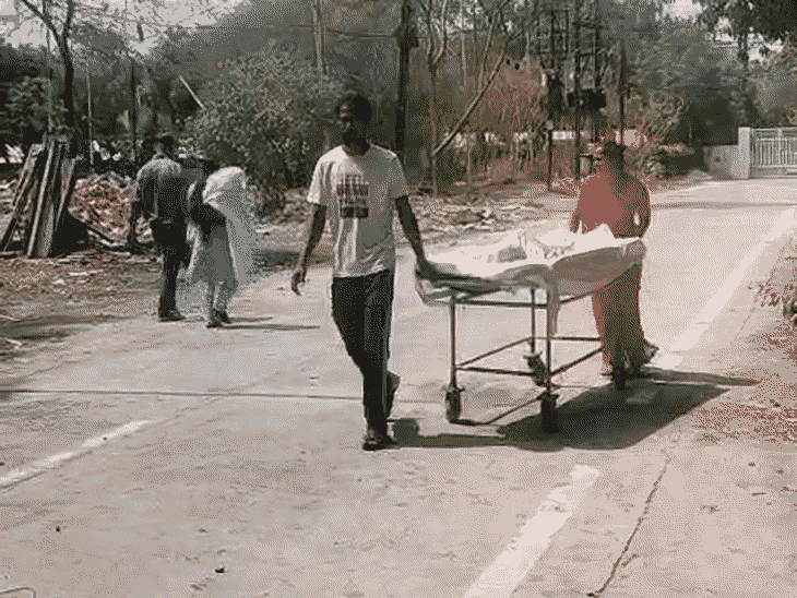 माता-पिता एक बीमार बच्चे को स्ट्रेचर पर एक अस्पताल से दूसरे अस्पताल ले जा रहे हैं।