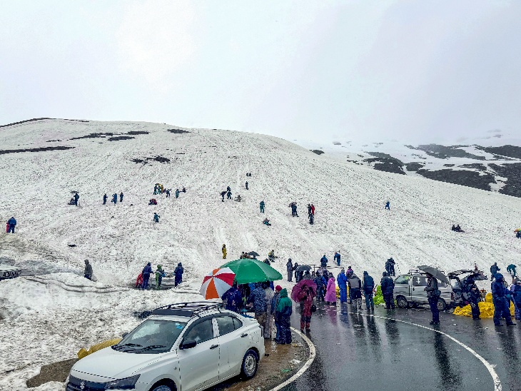 हिमाचल प्रदेश के मनाली में रोहतांग दर्रे पर बर्फ देखने के लिए पहुंचे टूरिस्ट। यहां बारिश भी हो रही है।