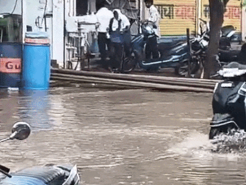 महेंद्रगढ़ में जलभराव के बीच जाते बाइक और स्कूटी सवार।