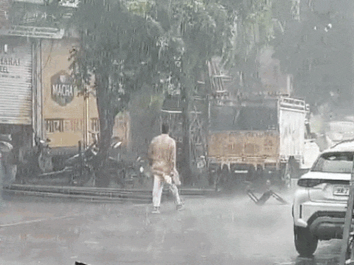 महेंद्रगढ़ में हुई झमाझम बारिश में भीगते हुए जाता युवक।