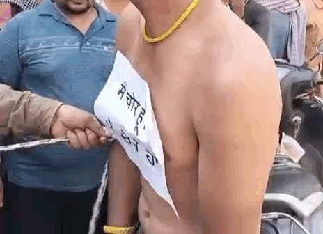 युवक को रस्सी से बांधते हुए लोग।