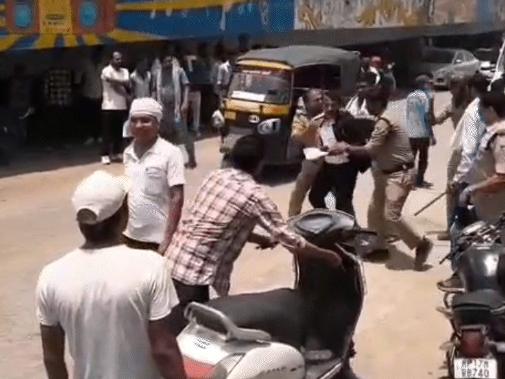 भीड़ के बीच से वकील को खींचते हुए पुलिसकर्मी।