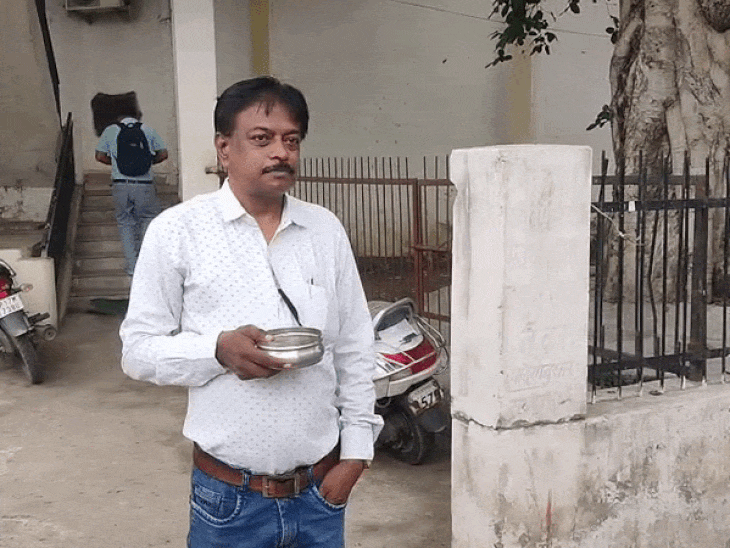 हाथ में कटोरा लेकर खड़ा कर्मचारी।