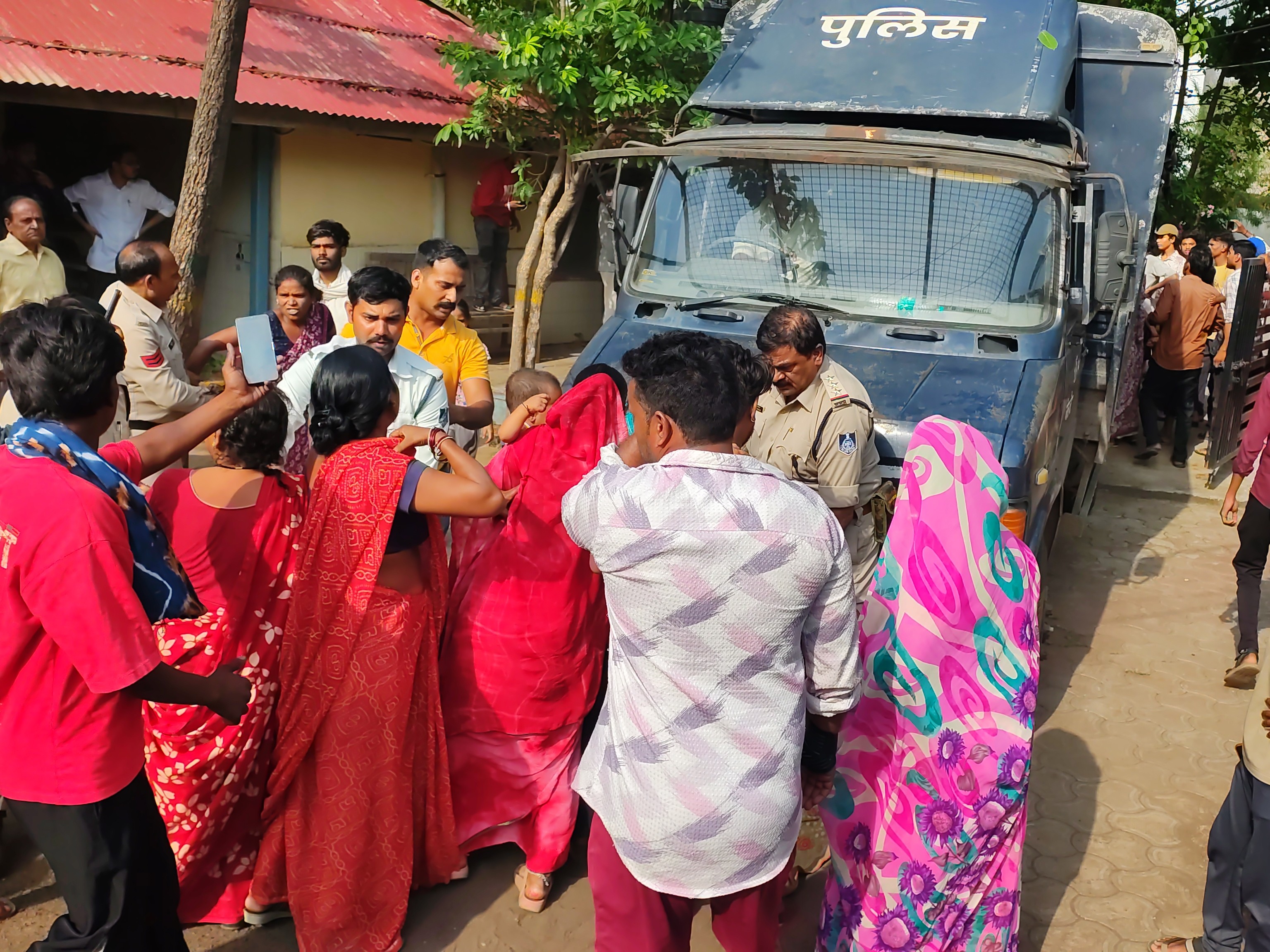 वाहन के आगे लेटे परिवार के सदस्य को हटाते पुलिसकर्मी।